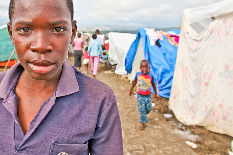 A young man stands in a tent city assembled inside the soccer stadium in Jacmel. The population of Jacmel before the Jan.