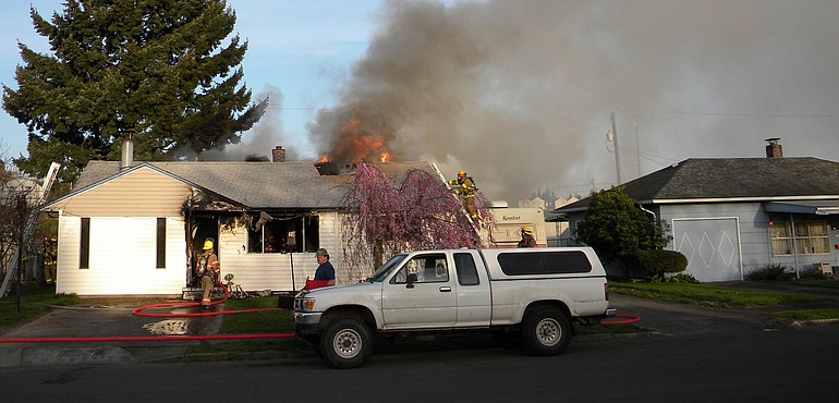 Flames erupt from the roof of a Fruit Valley home Thursday as firefighters work.