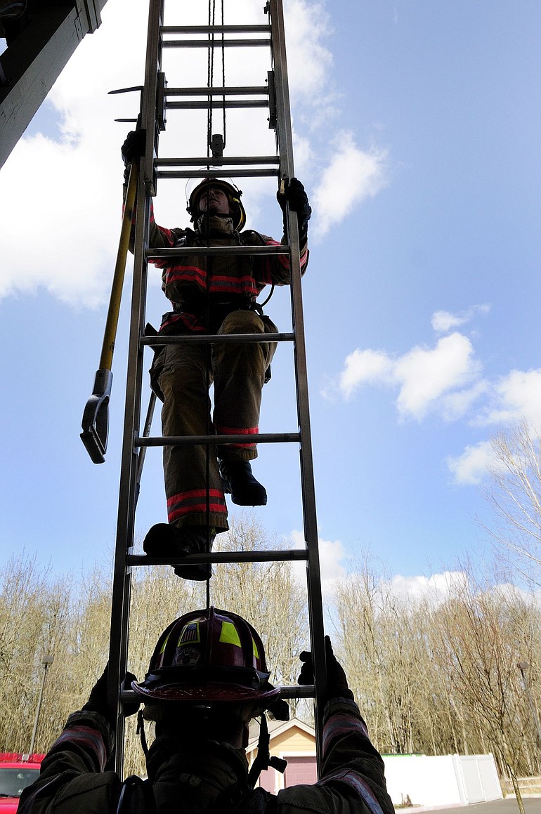 Vancouver Fire and Rescue firefighters Tom Cook, bottom, and Shane Parker train in a drill at the Mill Creek Apartments in Battle Ground Wednesday.