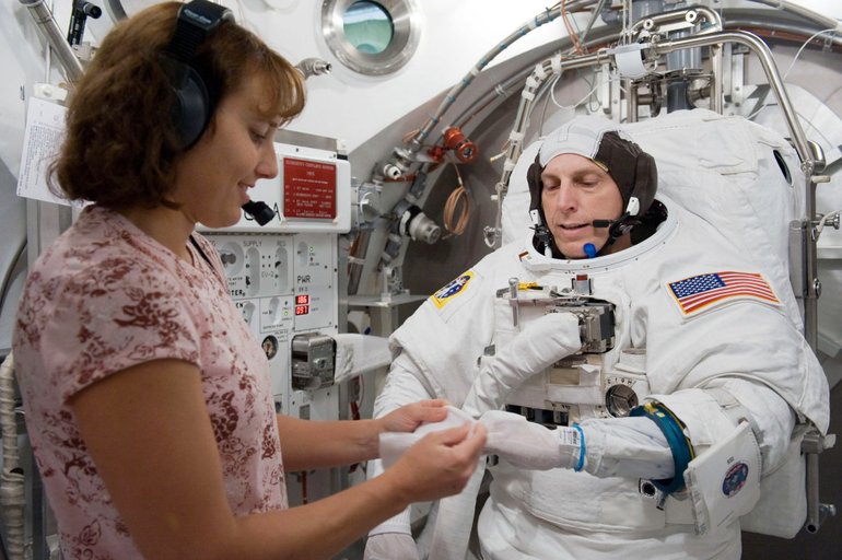 Dottie Metcalf-Lindenburger helps fellow astronaut Clay Anderson get his spacewalk suit ready for an airlock test at NASA's Johnson Space Center.