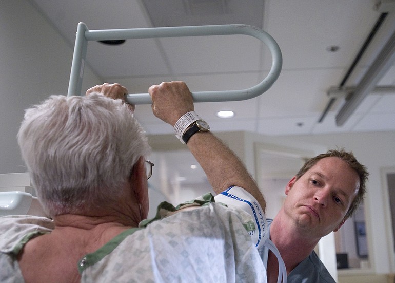 Radiologist Nathan Gisby, right, a 2009 Clark College graduate, puts a patient in to position for a chest X-ray at Southwest Washington Medical Center on Tuesday.