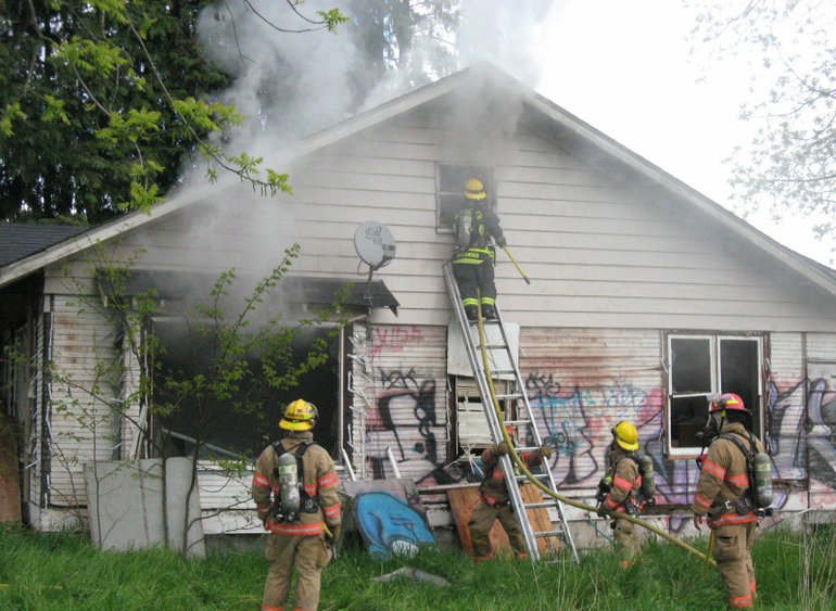 Firefighters fight a blaze at a vacant, boarded-up house at Northeast 94th Avenue and 105th Street on Tuesday afternoon.