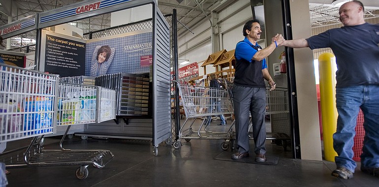 Costco employee Teddy Patrick, who is featured in a Goodwill Industries advertisement, shakes hands with customer Rod Burnett of Ridgefield.