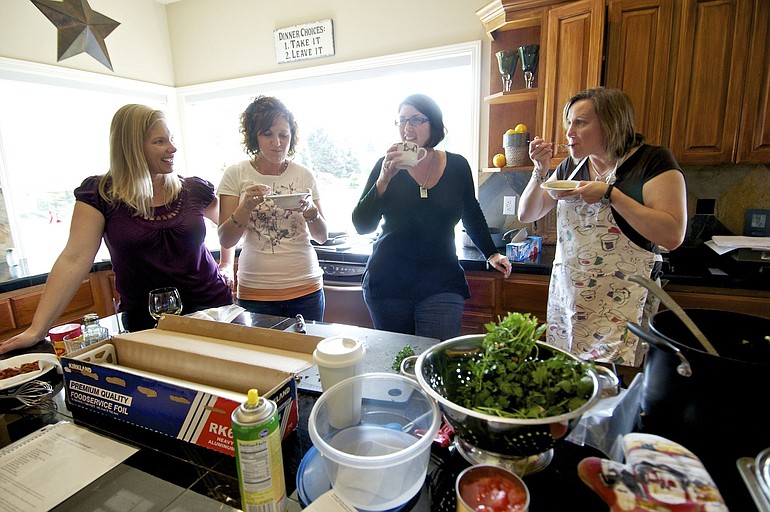 Amy Benson, left, Debbie Oster, Krista Colvin and Angela Fadlovich share a moment together during a cooking party for the Colvin family as a way to support Krista as she undergoes treatment for breast cancer.