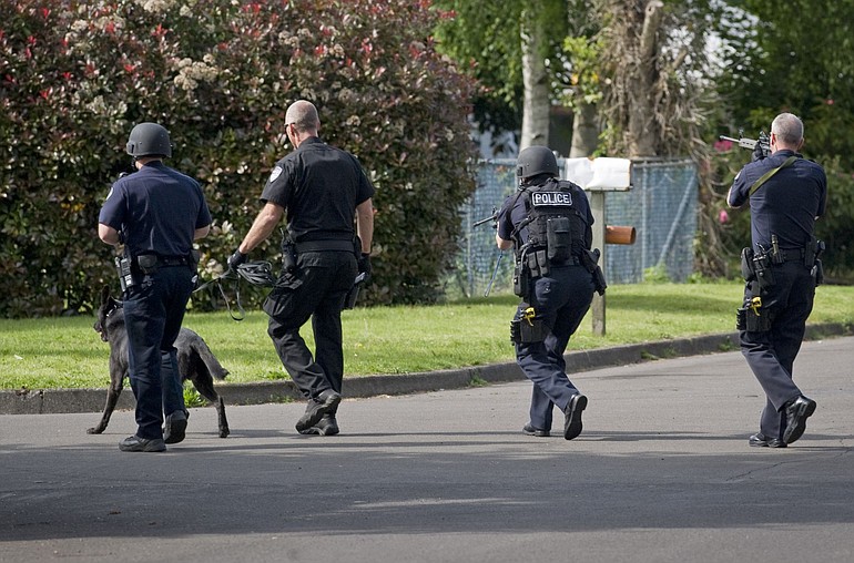 Vancouver police and a Clark County Sheriff's K-9 deputy approach a home at 32nd and X streets while attempting to serve a domestic violence warrant Sunday.