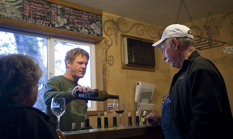 Wind River Cellars owner Joel Goodwillie, center, pours Allen and Jean Yanity, of Lake Bay a glass of wine inside the tasting room in Husum on May 19.