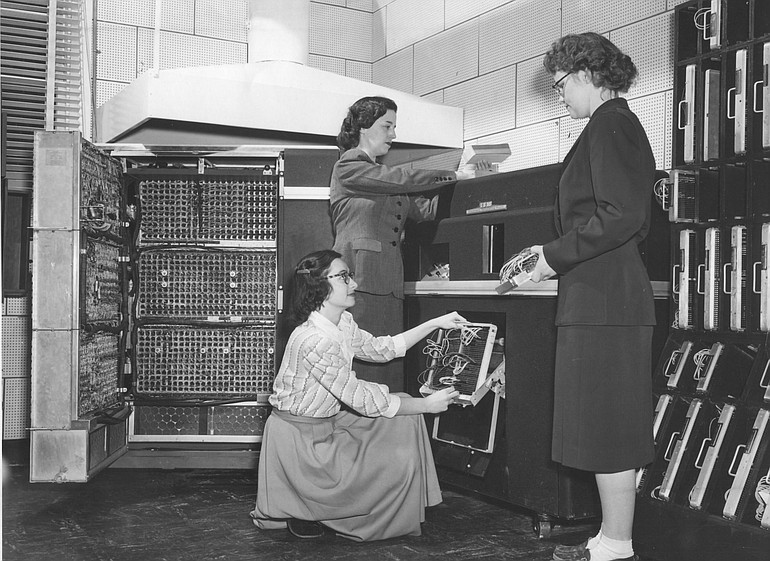 Phyllis Cady Johnson, right, works with an early IBM computer.