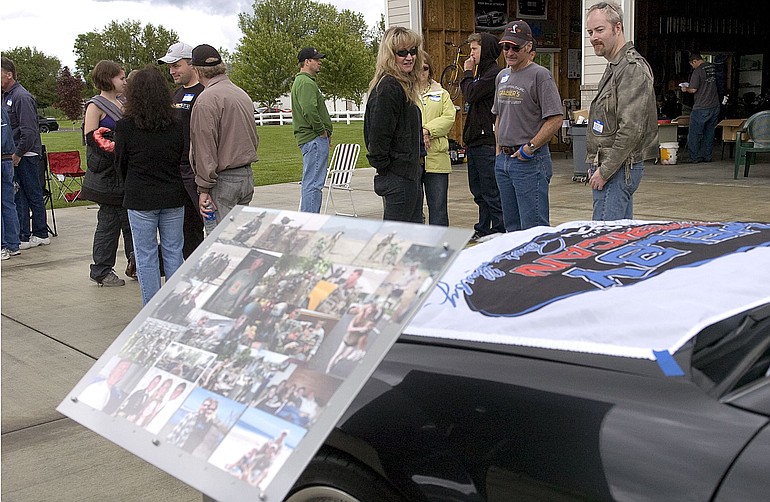 Barbie Coleman, center in black, looks at a flag draped across her fallen husband's car -- Mark Coleman was killed in Afghanistan on May 2. The flag is signed by Carroll Shelby, who teamed with Ford to create the Shelby Mustang line.