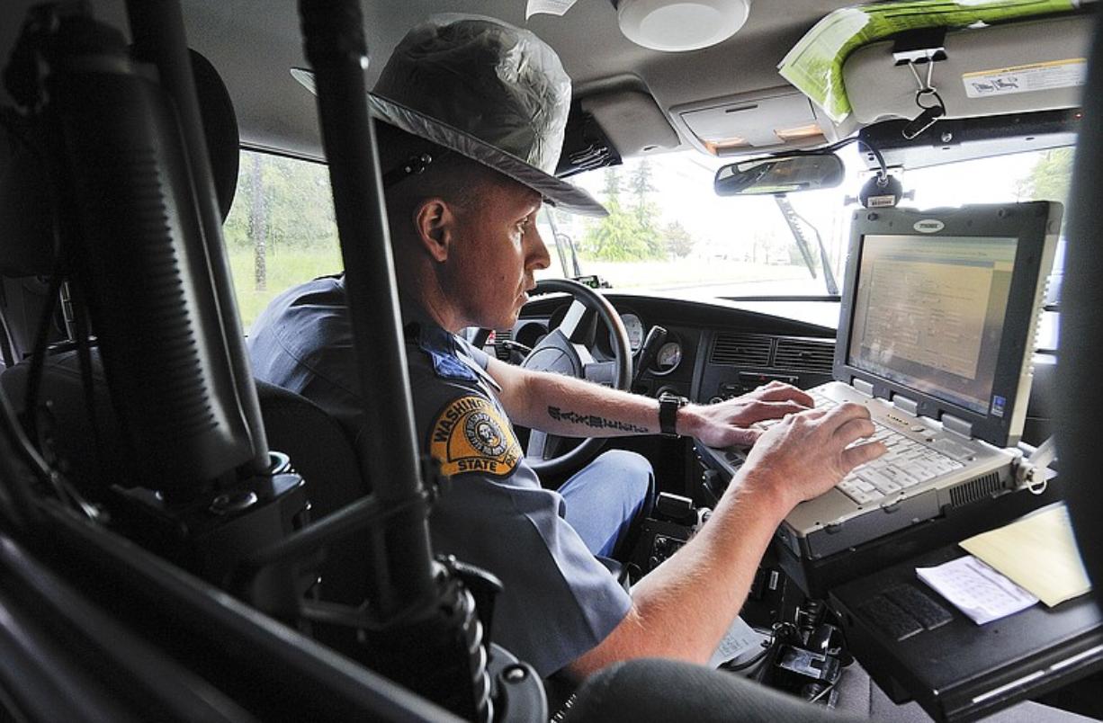 Washington State Patrol Trooper Steve Robley writes a ticket for a woman who was talking on her cell phone on Thursday, the first day of a revised law making improper cell phone use a primary violation.