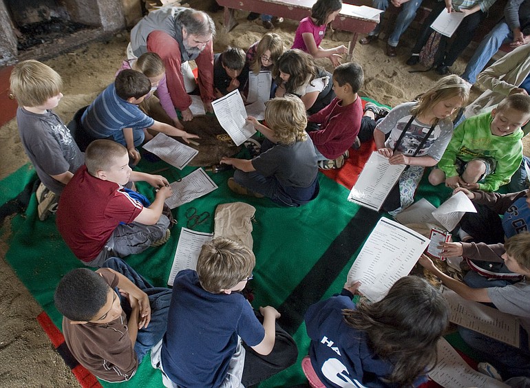 Fourth-graders from Daybreak Primary School get a lesson in what trading was like in the 1830s and 40s from National Park Ranger Doug Halsey, top left, inside a structure at the Fort Vancouver Village.