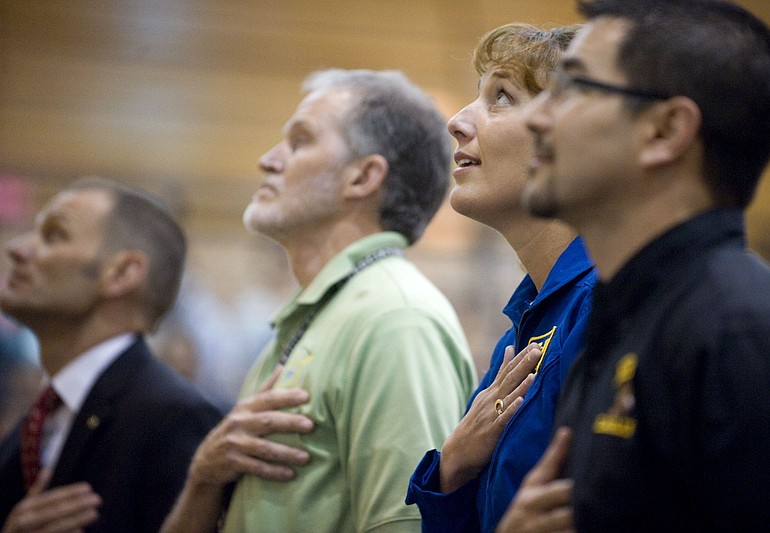 School Superintendent Steven Webb, from left, Hudson's Bay teacher and coach Tom Petersen, astronaut Dottie Metcalf-Lindenburger and Principal Bill Oman look toward the American flag during the singing of the National Anthem before Friday's assembly.