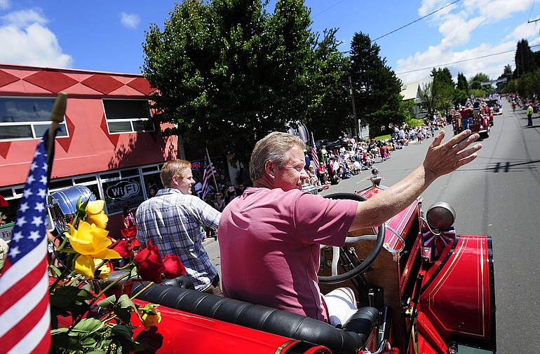 Brad Fletcher, right, of Vancouver, and his son, Tom, of Kennewick, wave from atop a 1927 Ahrens Fox firetruck.
