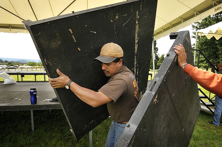 Mario Leon, a worker with The Party Place, helps take apart the main stage Monday at the Fort Vancouver National Historic Site, following Sunday's fireworks show.