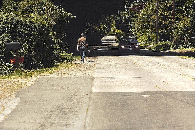 Chris Kellogg, co-chairman of the Old Evergreen Highway Neighborhood Association, walks west along the busy Old Evergreen Highway on Tuesday. The city recently landed a $925,000 federal grant to add a pedestrian pathway through the residential area.