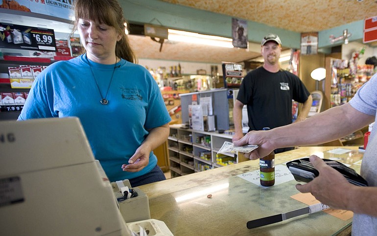 Jeri Connolly, co-owner of the Washougal River Mercantile, rings up customers while her son Charles Fawver looks on.