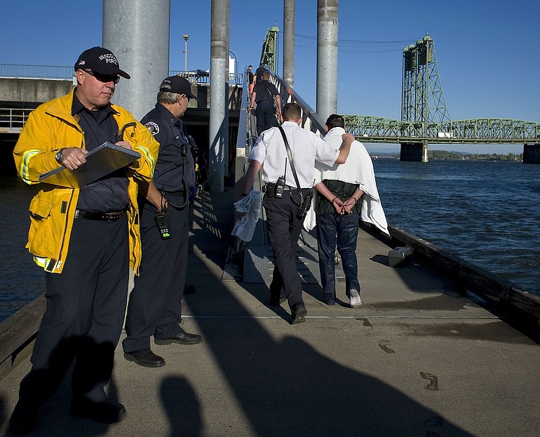 A rescuer escorts a man, right, wearing towel, up the ramp of a boat dock along the Columbia River last month after the man gave a cab driver a suicide note and jumped into the water.
