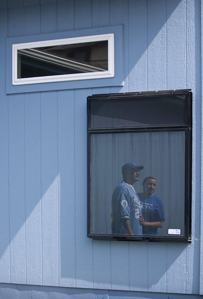 Rocky Orozco, left, and Isabel Reyes are reflected in the solar room heater panel glass attached to the southwestern corner of their new Kansas City, Kan., house.