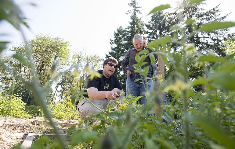 Volunteer Bruce Hall, right, advises Jeff Forney about his garden plot at Aurora Place apartments in Vancouver.