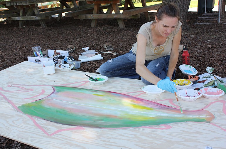 Laura Nappi, salmon in the classroom coordinator for Columbia Springs, paints a salmon on a donation board to be used during the second &quot;Hooked&quot; fundraising event on Thursday.