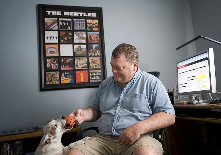 Jason Spicer, 48, a Washington State University online student, plays with his dog Zaika near his home computer in Washougal. The former Microsoft employee will finish a business degree this semester, without once visiting Pullman.