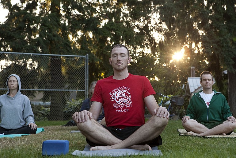 Zach Barnes meditates at the start of a yoga class taught by Emily Oliva in Arnada Park.