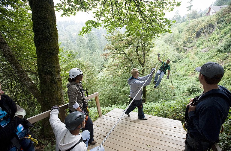 Customers and tour guides meet on a platform after taking turns on the four zip lines set-up in Washougal.