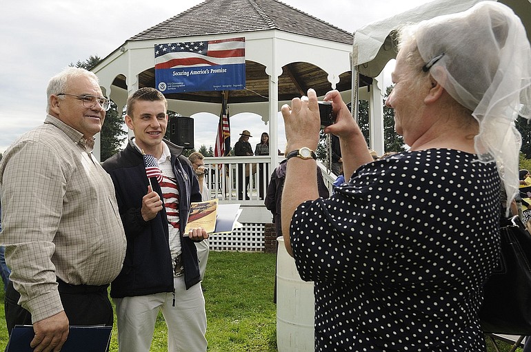 Zoya Babiy of Vancouver, right, takes a photo of husband Andrey Babiy, left, and their son Ilya Babiy after they became U.S. citizens Friday morning on the grounds of Fort Vancouver National Historic Site. The Babiy family came to the U.S.