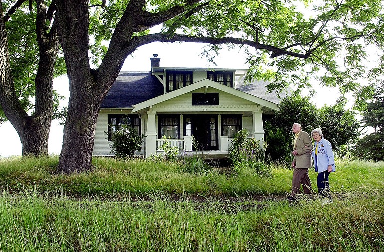 Ed and Dollie Lynch walk together past an old farm house which sits on 10-acres of land they owned off Franklin St. in Vancouver in 2002.