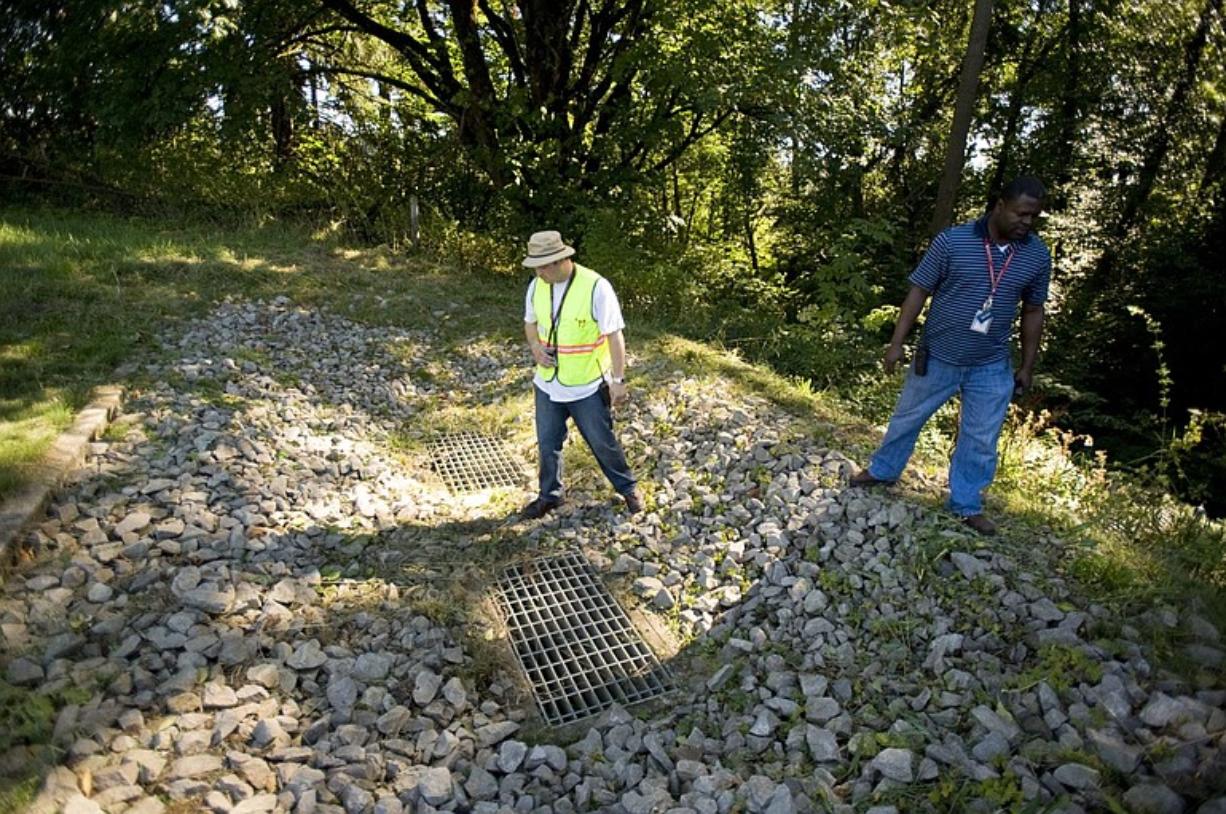 WSUV grounds specialist John Benson and facilities operations director James Martin stand atop the top end of a drain that will settle out silt through a series of a dozen rock gabions below.