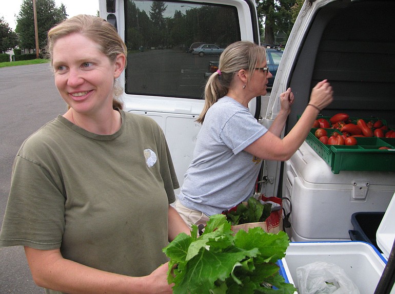 April Jones, an organic CSA farmer from Ridgefield, left, distributes fresh produce to Fruit Valley resident Michelle May.