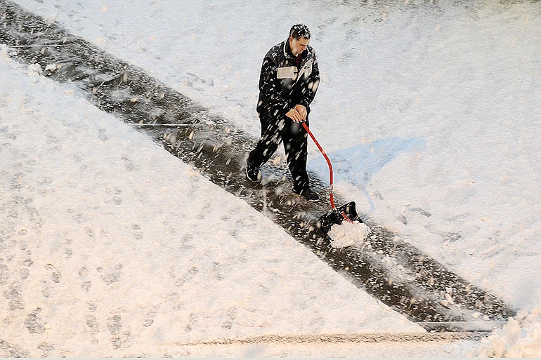 A Regal Cinemas employee shovels snow outside the City Center theater in Vancouver in December 2009.