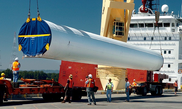 Work crews offload a turbine tower section from a ship at the Port of Vancouver.