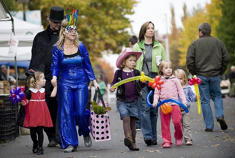 The Lyons family, from left, Macy, 3, Craig, Joy and Jenna, 6, and the Rilling family, Michelle, Kira, 5, and Natalie, 3, spend part of Halloween at the Vancouver Farmers Market on Sunday afternoon.