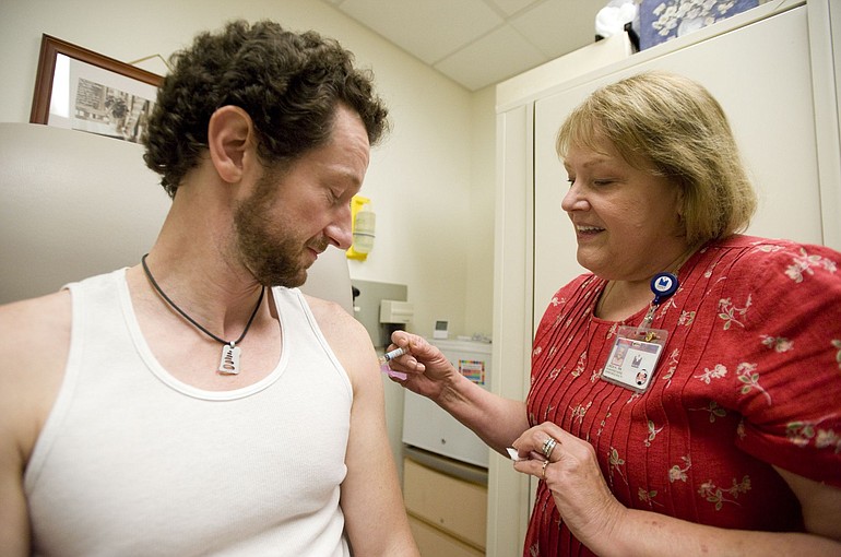 Linda Heilweck, an employee health nurse at Legacy Salmon Creek Medical Center, gives a flu shot to hospital financial counselor Randy Moyer.