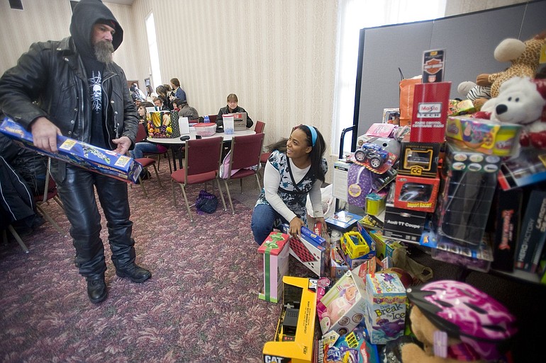 Biker Steve Powers of Vancouver drops off a toy as Sheri Huckins organizes gifts Saturday.