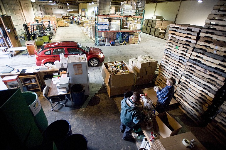 Food bank warehouse manager James Fitzgerald, lower left, and employee Dave Gordon sort through food donated during last weekend's Walk &amp; Knock food drive as another delivery pulls in Thursday.