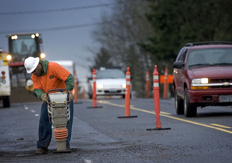 Construction worker Tim Barner on Monday repairs a hole dug to survey existing utility lines as part of the road-widening project on Northeast 112th Avenue at Northeast 18th Street.