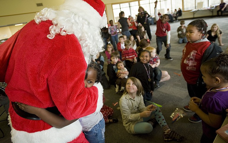 Tylia Hadley, 6, of Vancouver gives Santa a big hug during the party.