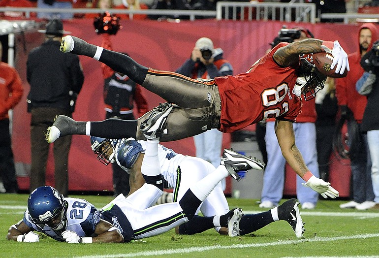 Tampa Bay Buccaneers tight end Kellen Winslow (82) dives over Seattle Seahawks cornerback Walter Thurmond (28) to score a third-quarter touchdown Sunday.