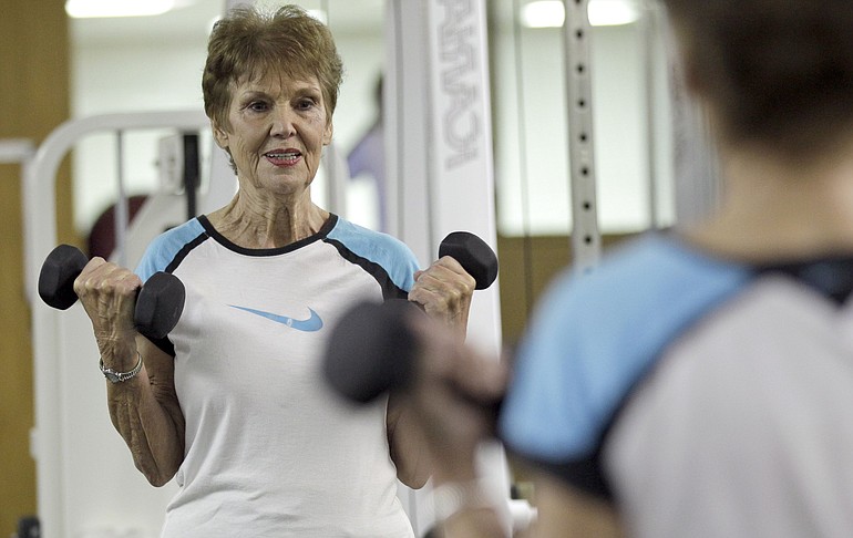 Esther Robinson, 93, watches herself in a mirror while lifting weights during a Dec.