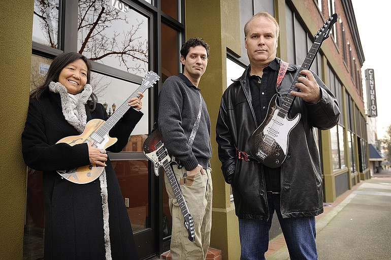 Pure Imagination LLC partners, from left, Miriam Kim, Philip Odom and Mike Wallace hold their top-selling toy, the Paper Jamz electric guitar, outside their new downtown Vancouver office.