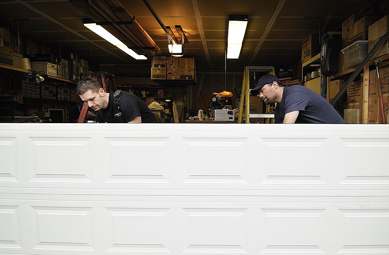 Aaron Cottrell, left, and Phil Baxter, overhead door technicians with Brown's Overhead Door Company, install a new garage door.