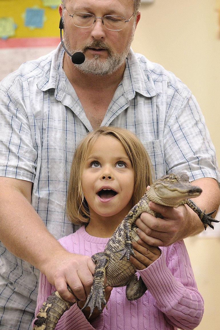 Richard Ritchey, The Reptile Man in the Pacific Northwest for 20 years, is pictured here in October giving Maggie Hernandez, 7, an opportunity to hold alligator D.B. Cooper at Echo Shaw Elementary School in Cornelius, Ore.