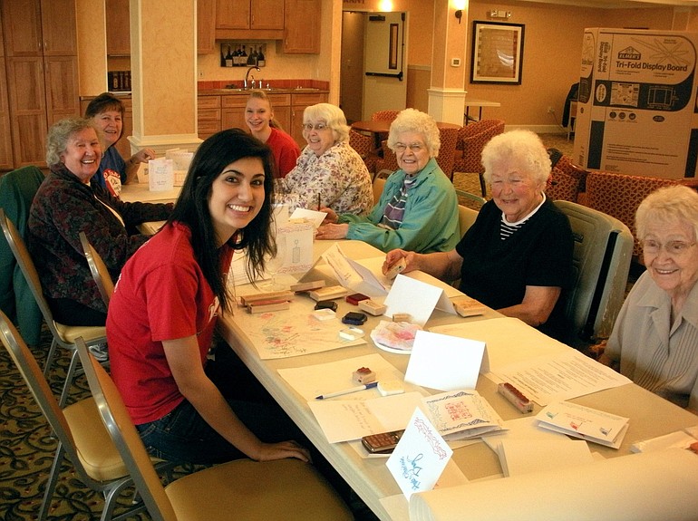 Camp Fire Girls Meena Mortazavi and Maegan Davidson work with residents of Van Mall Retirement Center to make cards for overseas troops.