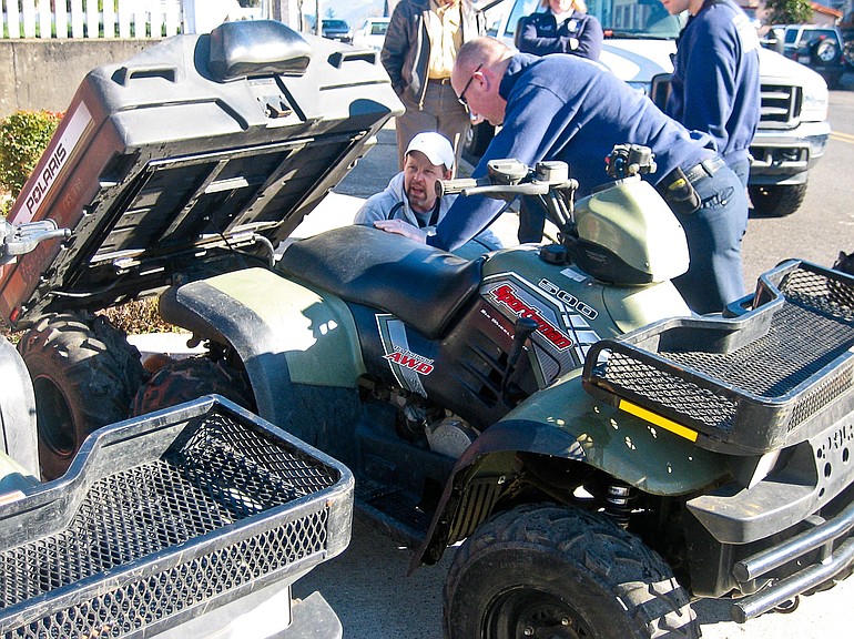 Jeff Haxby, kneeling at left, checks out the rear dump bed of a six-wheel-drive Polaris all-terrain vehicle on Wednesday with Maury Hildenbrand, a medic with Skamania County Emergency Medical Services.