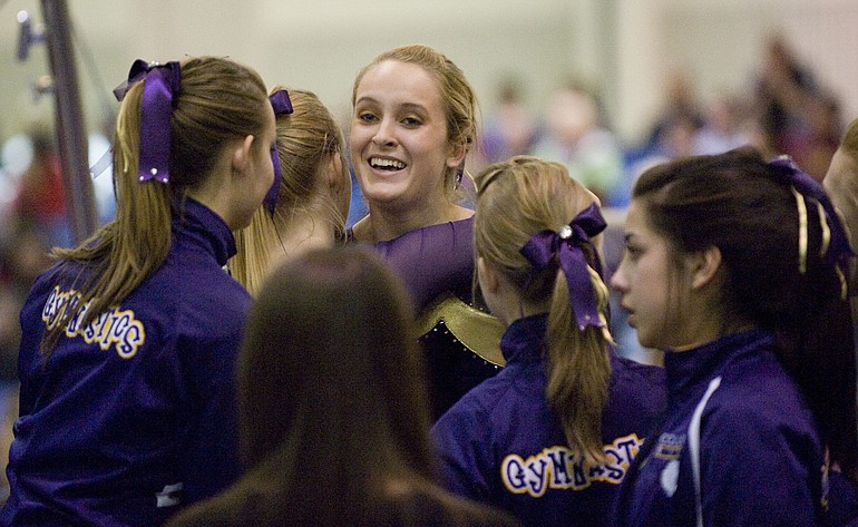 Columbia River's Jordan Hess is congratulated by teammates after competing on the uneven bars at the Class 3A state championships despite a torn ACL.