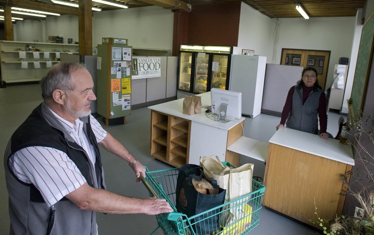 Vancouver Food Cooperative member David Page of Felida heads out to his car after picking up his order of fresh produce, crackers and bread while volunteer Sara Spiegel, back right, staffs the cash register.