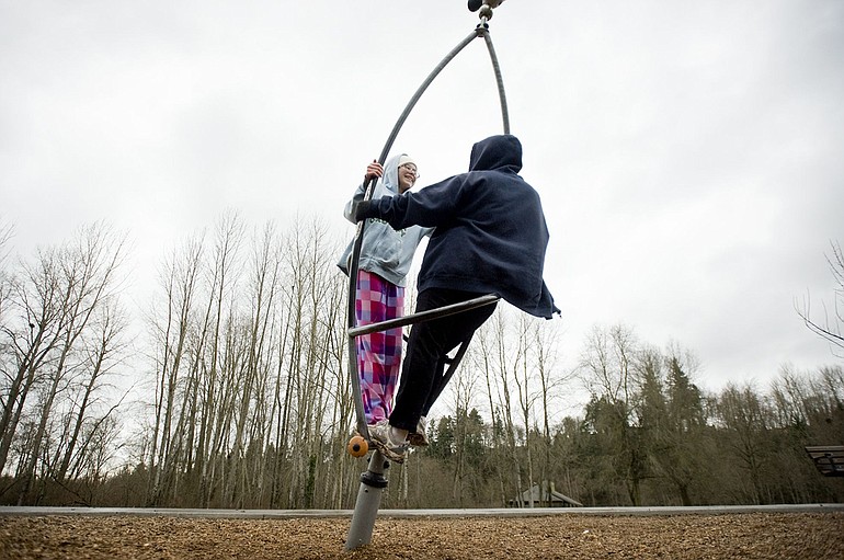 Sisters Rachael, 13, left, and Kendra Harmon, 18, spin the rainy Sunday away on playground equipment at Salmon Creek Park.
