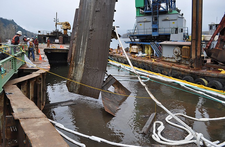 Contractors remove debris from the barge Davy Crockett, enabling divers better access to the point where the barge will be severed.
