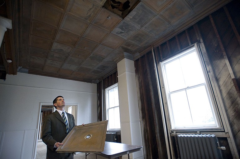 Michael True holds an original two-foot-square pressed-tin ceiling panel Friday while explaining renovation plans in the east wing.